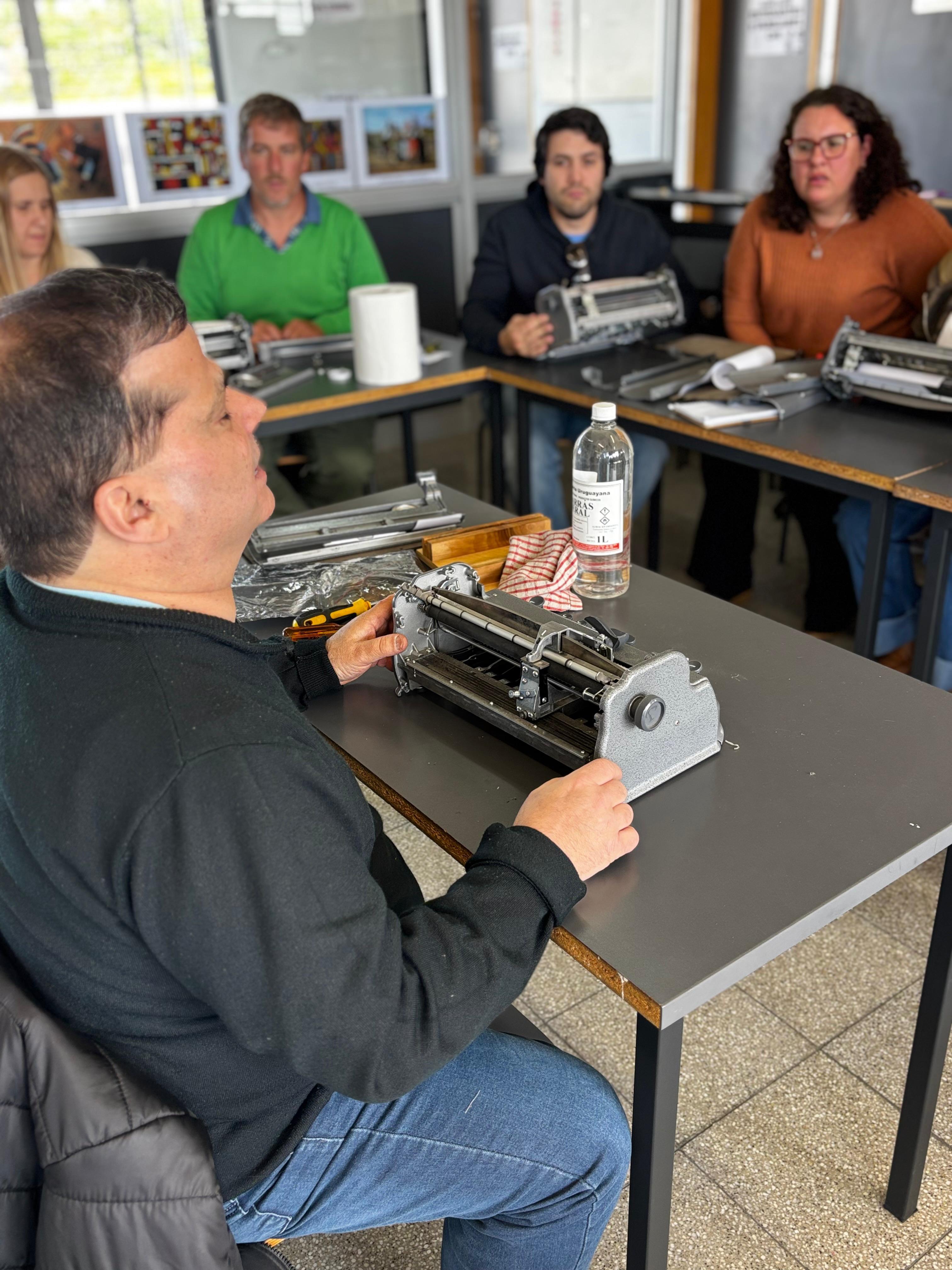 El facilitador, sentado en una mesa, mostrando las funcionalidades de la máquina Perkins.