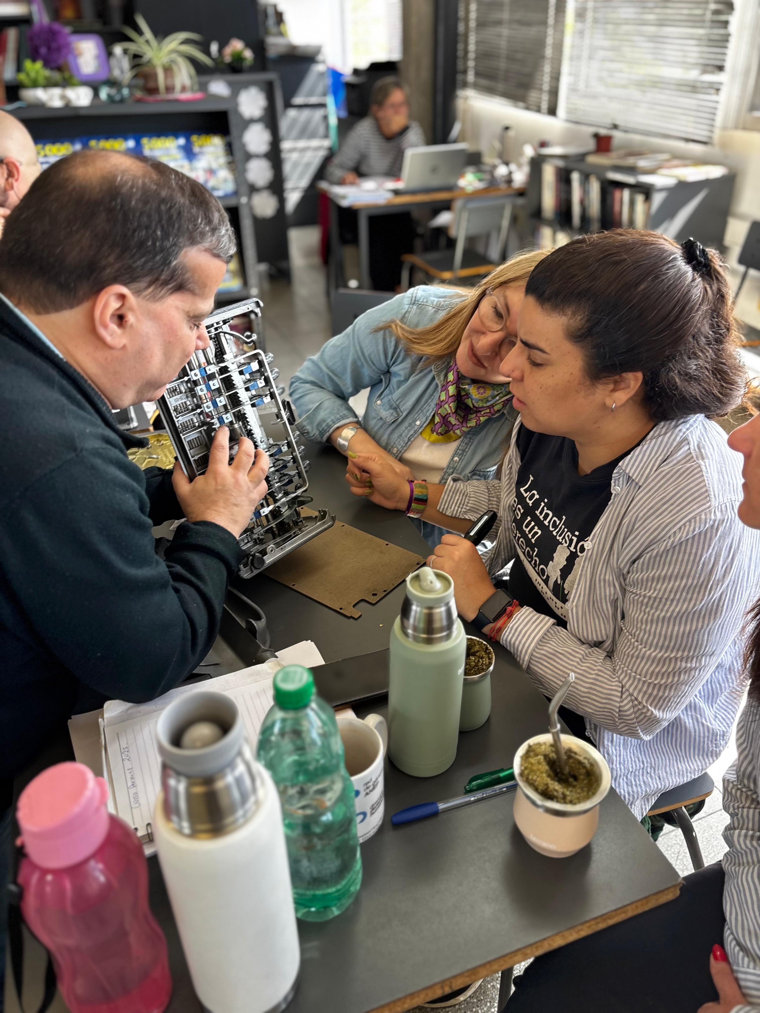 Pedro Vázquez, el facilitador, explicando la máquina desarmada, desde su interior, a dos funcionarias. 